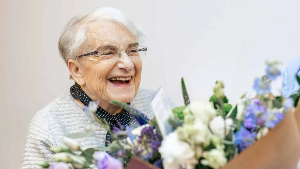 A woman smiling with a bunch of flowers.